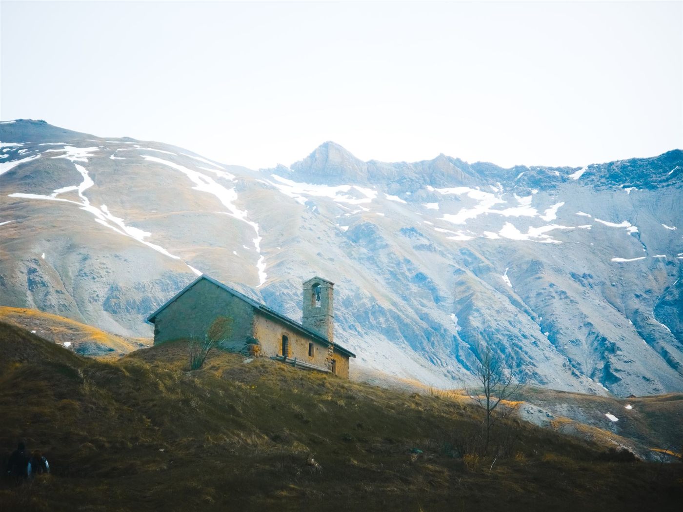 Stone chapel on a slope below the mountains